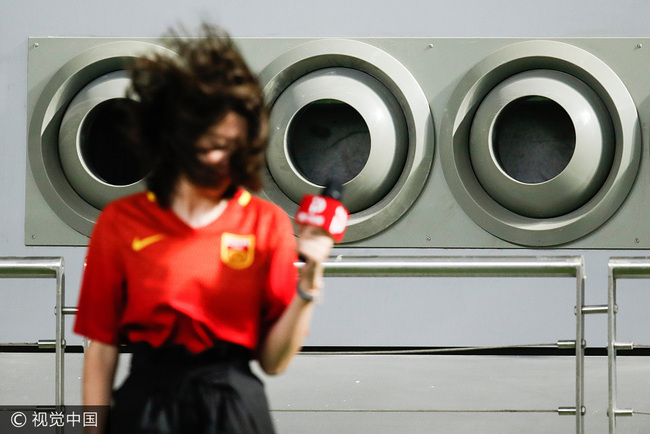 A Chinese reporter stands in front of the ventilators at the Khalifa Stadium in Doha, Qatar on September 4, 2017. The air conditioning system will keep temperatures at around 26 degrees Celsius during the World Cup qualifier between China and Qatar. [Photo: VCG] 