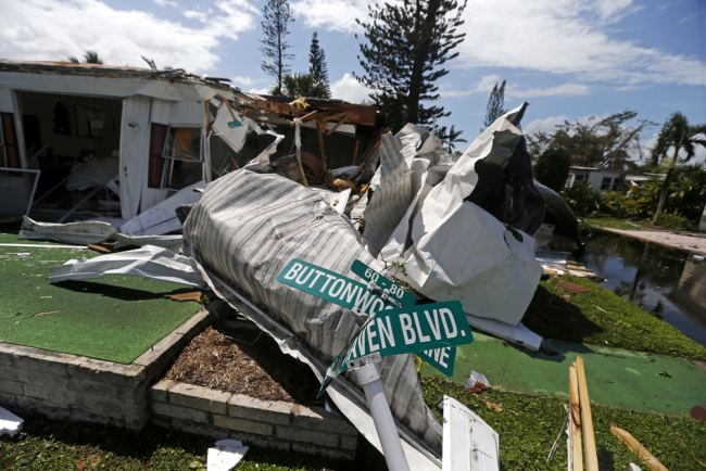 Damaged street signs sit among debris in the Naples Estates mobile home park in the aftermath of Hurricane Irma in Naples, Fla., Sept. 11, 2017. [Photo: AP/Gerald Herbert]