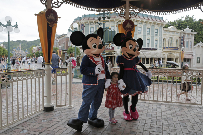 File photo: a girl poses with Mickey and Minnie Mouse at the Hong Kong Disneyland. [Photo: AP/Kin Cheung]