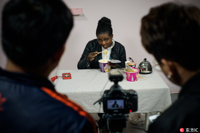 Ruth, a 22-year-old woman from Nairobi, Kenya, who studies at Tianjin Normal University, tastes food and gives her comments on a food review video in Tianjin. [Photo: IC]