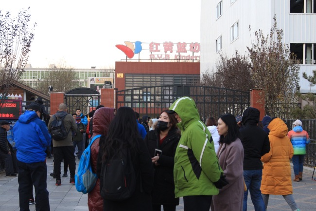 Parents gather outside the gate of the RYB Education New World kindergarten in Chaoyang District of Beijing on Thursday, November 23, 2017. [Photo: IC/Zhou Min]