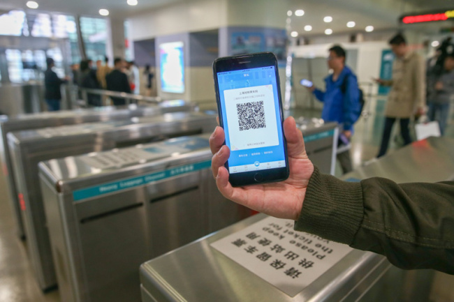 A passenger shows a QR code through the Metro Metropolis app on October 30, 2017. [Photo: Xinhua]