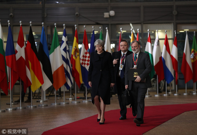 Theresa May, U.K. prime minister, left, and Tim Barrow, U.K. permanent representative to the European Union (EU), right, arrive at a European Union (EU) leaders summit at the Europa Building in Brussels, Belgium, on Thursday, Dec. 14, 2017. [Photo: VCG]