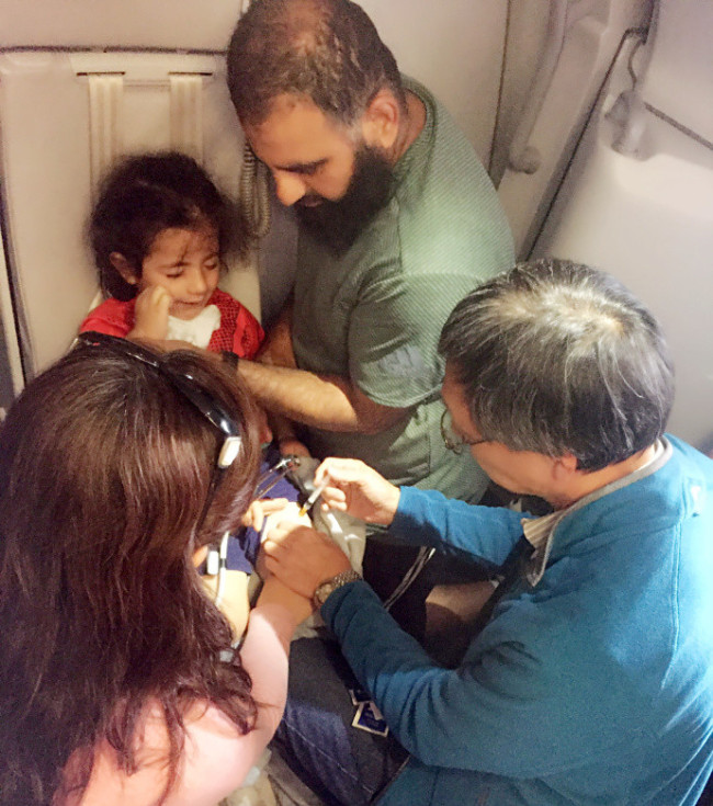 A doctor gives an emergency treatment to a boy suffering from a severe allergic reaction on a China Southern Airlines flight from Sydney, Australia to Guangzhou, December 14, 2017. [Photo: provided by the air crew to China Plus]