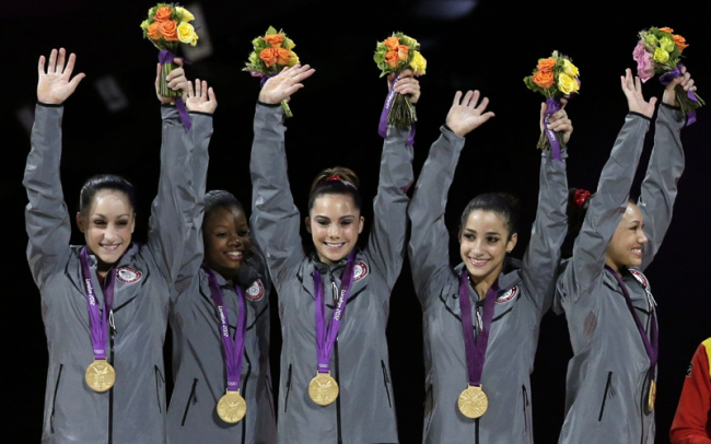 U.S. gymnasts, left to right, Jordyn Wieber, Gabrielle Douglas, McKayla Maroney, Alexandra Raisman, Kyla Ross raise their hands on the podium during the medal ceremony during the Artistic Gymnastic women's team final at the 2012 Summer Olympics, Tuesday, July 31, 2012, in London. Team U.S. won the gold. [Photo: AP/Gregory Bull]
