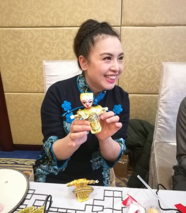 A participant was making Peking Opera Puppet during the event. [Photo: from China Plus]