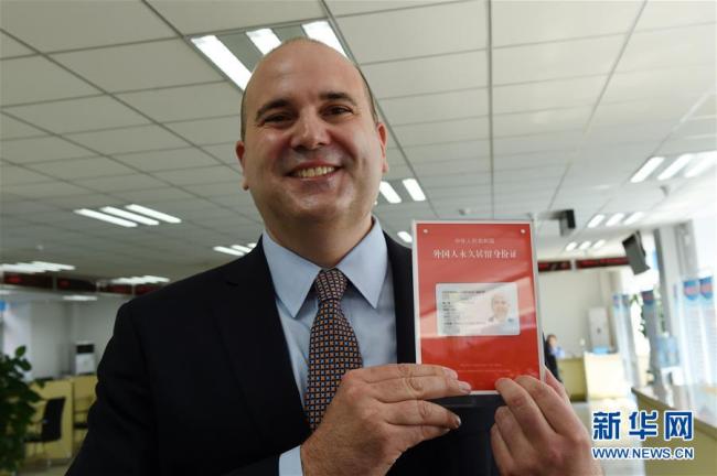 A foreigner shows the new version permanent residence identity cards in Beijing on June 16. [File photo: Xinhua]