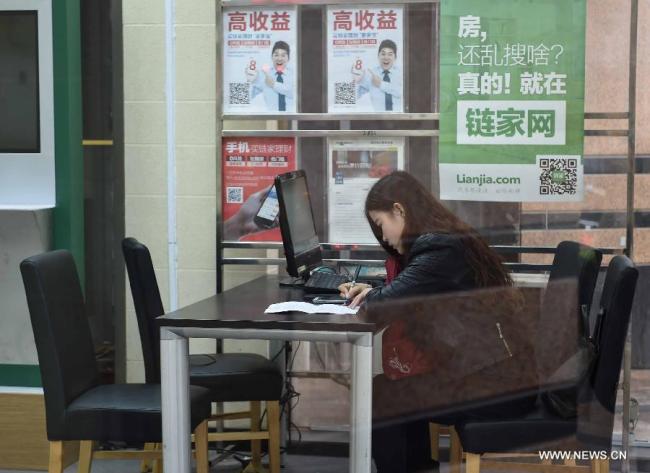 A staff member works in a real estate agency in Beijing, capital of China, March 31, 2015.[Photo: Xinhua]