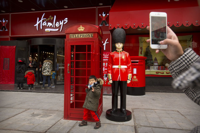 A boy poses for a smartphone photo outside of Hamleys toy store during its grand opening in Beijing, Saturday, Dec. 23, 2017. [Photo/AP/Mark Schiefelbein]