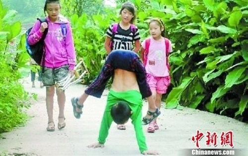 Yan Yuhong "walks" to school on his hands in Yinbin, Sichuan Province, in 2012. [File Photo: Chinanews.com]