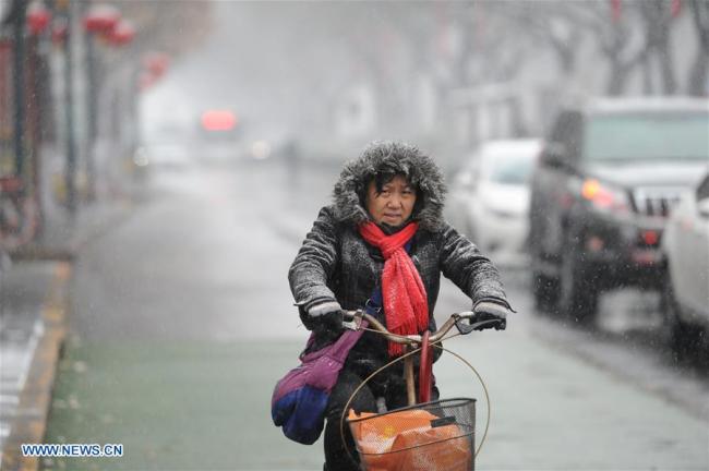A woman rides amid snowfall in Xi'an, capital of northwest China's Shaanxi Province, Jan. 3, 2018. Xi'an greeted a snowfall Wednesday. [Photo: Xinhua/Zhang Bowen]