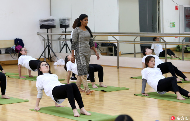 A professional from India is instructing Chinese students to perform yoga in the yoga institution founded in Yunnan Minzu University. Photo is taken on April 27, 2017. [Photo: From dfic.cn]
