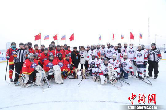 Participants from northeast China's Heilongjiang Province and Russia's Amur Region taking part in an ice hockey friendly match between the two countries take a group photo near the site of the match on the Heilongjiang River, the border river between China and Russia, on January 14, 2018. [Photo: Chinanews.com]