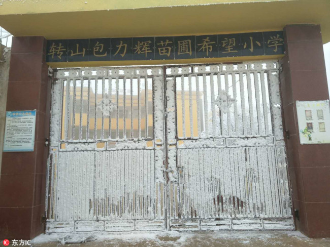 The gate of the Zhuanshanbao Primary School of Ludian County, Yunnan Province, is covered in ice, January 8, 2018. [Photo: IC]