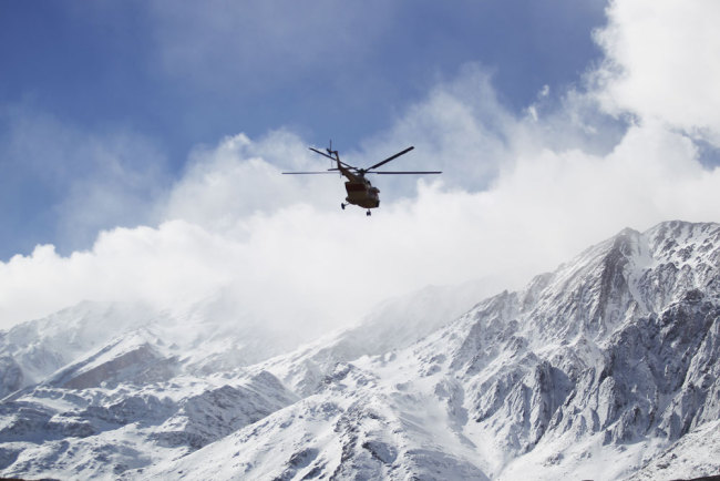 In this photo provided by Tasnim News Agency, a rescue helicopter flies over the Dena mountains while searching for wreckage of a plane that crashed on Sunday, in southern Iran, Monday, Feb. 19, 2018. Iranian search and rescue teams on Monday reached the site of a plane crash the previous day that authorities say killed all 65 people on board, Iran's Press TV reported.[Photo: Ali Khodaei/Tasnim News Agency via AP]