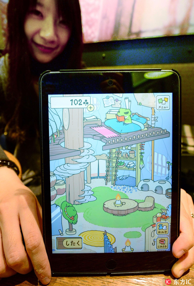 A woman in Beijing shows a scene from "Tabikaeru" (Travel Frog), a Japanese game app, on Jan. 30, 2018. [Photo: IC] 