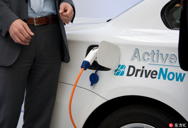 A DriveNow employee demonstrates how an electric car is charged. Forty electric cars of BMW were introduced to become part of the Berlin car-sharing fleet DriveNow. [File photo: IC] 