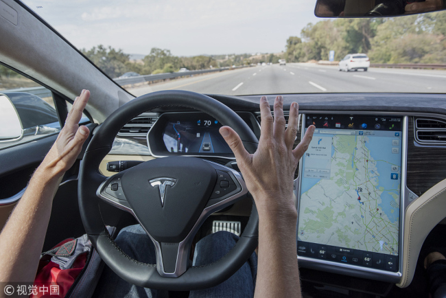 A man drives a Tesla Model S car equipped with so-called "Autopilot" technology in California on October 14, 2015. [Photo: VCG]