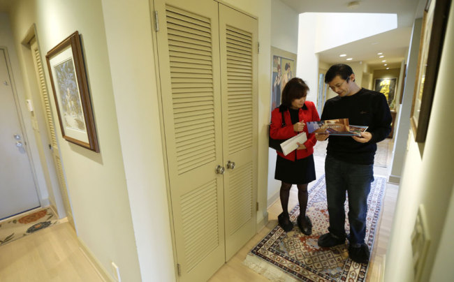 Janie Lee, left, a residential specialist with John L. Scott Real Estate, shows a home for sale to her client, Hongbin Wei, of Beijing, China, on Dec. 18, 2014, in Medina, near Seattle. [Photo: AP/Ted S. Warren]