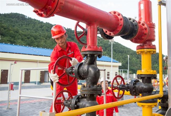 Two workers inspect equipments at a newly-operated dehydration station of Fuling shale gas project in southwest China's Chongqing Municipality, May 24, 2016. [Photo: Xinhua]