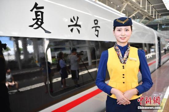 A crew member stands in front of a Fuxing bullet train developed by CRRC Changchun Railway Vehicles. [File photo: Chinanews.com]