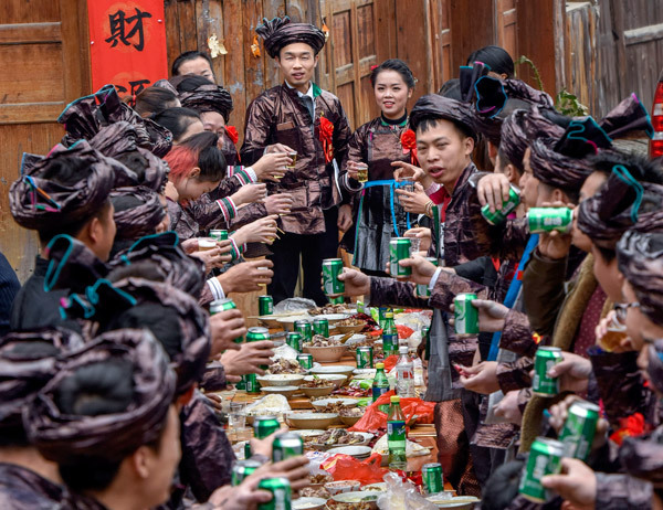A newly married couple raise a toast to guests at their wedding feast in Qiandongnan Miao and Dong autonomous prefecture in Guizhou province in January, 2017. [Photo: China Daily]
