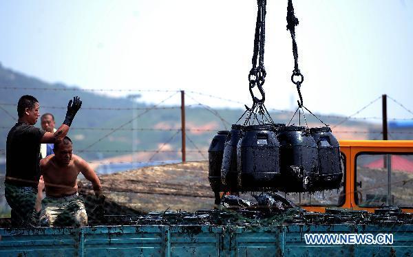 Workers transport barrels of crude oil during the oil spill cleanup operation near Xingang Harbor in Dalian City, northeast China's Liaoning Province, July 25, 2010. (Xinhua/Yao Jianfeng)