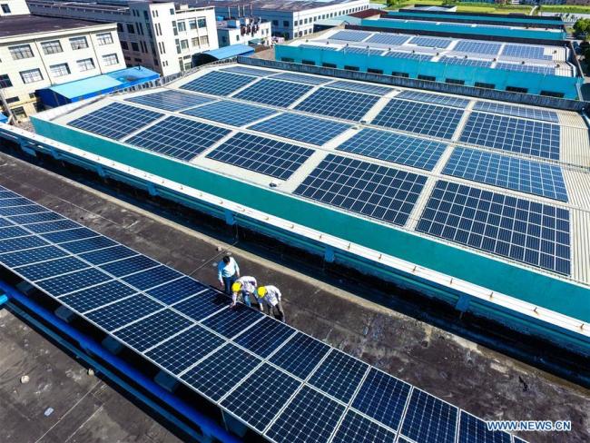 Technicians check solar energy equipment on a roof in Cixi City, east China's Zhejiang Province, May 10, 2017.[Photo: Xinhua]