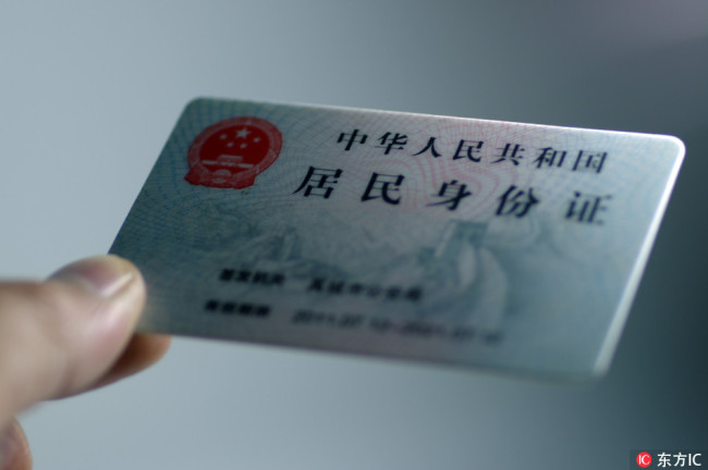 A man holds a resident identification card. [File Photo: IC]