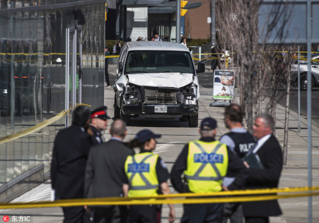 Police are seen near a damaged van after a van mounted a sidewalk crashing into pedestrians in Toronto on Monday, April 23, 2018. [Photo: The Canadian Press via IC/Aaron Vincent Elkaim]