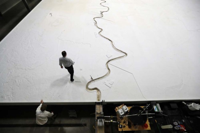 In this March 29, 2018 photo, Rudy Simoneaux, above, engineer manager for the Louisiana Coastal Protection and Restoration Authority, and Joseph McClatchy, coastal resources program specialist, walk on a replica of the lower Mississippi River in Baton Rouge, La. The model will help experts study the river and how sediment can be used from it to fight coastal erosion. [Photo: AP/Gerald Herbert]