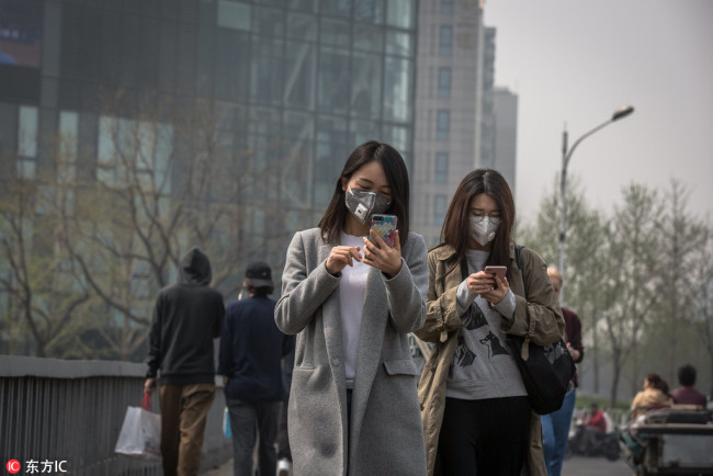 Chinese women wearing protective masks walk on the street during a polluted day in Beijing, China, 02 April 2018.[Photo: IC]