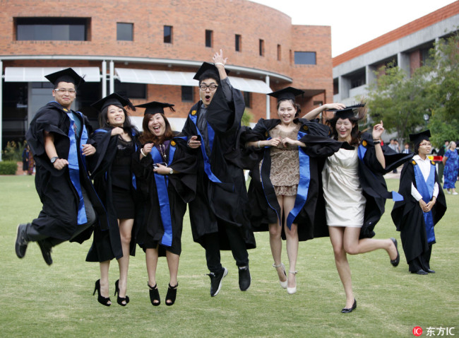 Chinese students studying abroad dressed in academic gowns pose for a graduation photo at Curtin University in Perth, Western Australia, on February 11, 2012. [Photo: IC]