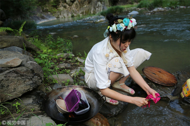 Zhang washes kitchen ware in the brook. [Photo/VCG]