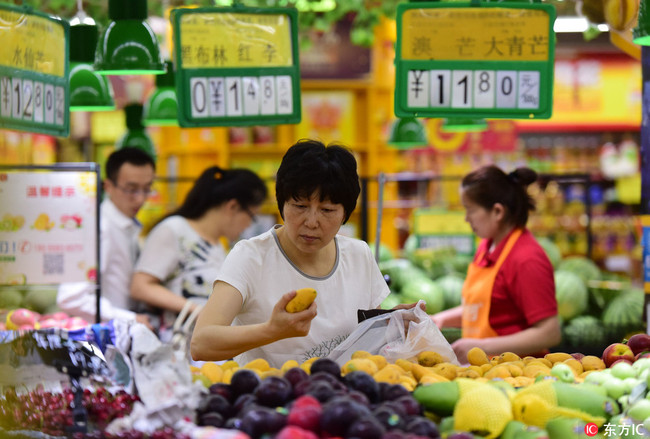 A resident picks fruits at a supermarket in Fuyang, Anhui Province on June 9, 2018. [Photo: IC]