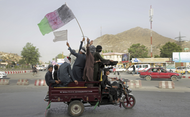 Taliban fighters and their supporters carry a representation of the Afghan national flag and a Taliban flag while riding in a motorized vehicle, in Kabul, Afghanistan, Sunday, June 17, 2018.[Photo: AP/Massoud Hossaini]