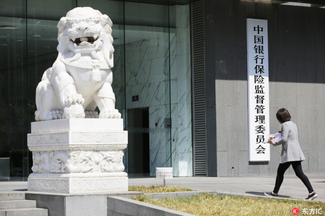 A woman walks past the headquarters of China Banking and Insurance Regulatory Commission (CBIRC) in Beijing on April 8, 2018. [File Photo: IC]