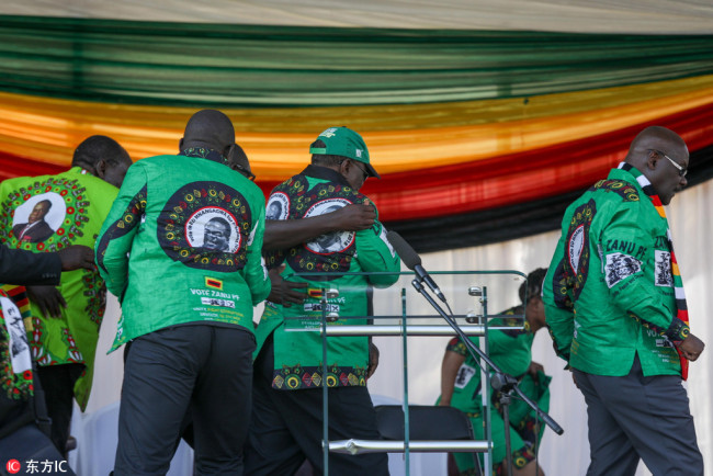 Members of the Zimbabwe African National Union - Patriotic Front (ZANU-PF) shield Zimbabwean vice president Constantine Chiwenga (C) away after a bomb went off during a rally addressed by President Emmerson Mnangagwa (not pictured), at White City Stadium in Bulawayo, Zimbabwe, 23 June 2018. [Photo: EPA/.INGER]