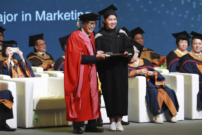 Hong Kong tycoon Li Ka-shing presents an award to Huang Yanting, one of the most outstanding graduates at Shantou University this year, at the Guangdong-based university's graduation ceremony on Friday. [Photo: China Daily]