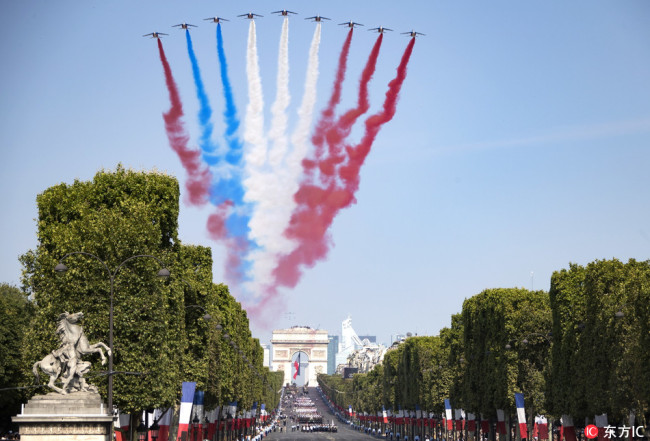 Alpha jets fly over the Arc de Triomphe leaving a red, white and blue trails during the annual Bastille Day military parade on the Champs Elysees avenue in Paris, France, 14 July 2018. [Photo: IC]