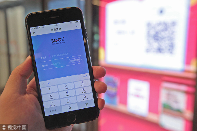 A customer demonstrates registration via QR code scanning at the Abu e self-service bookstore in Longgangcheng branch, Shenzhen Bookmall, July 17, 2018. [Photo/VCG]
