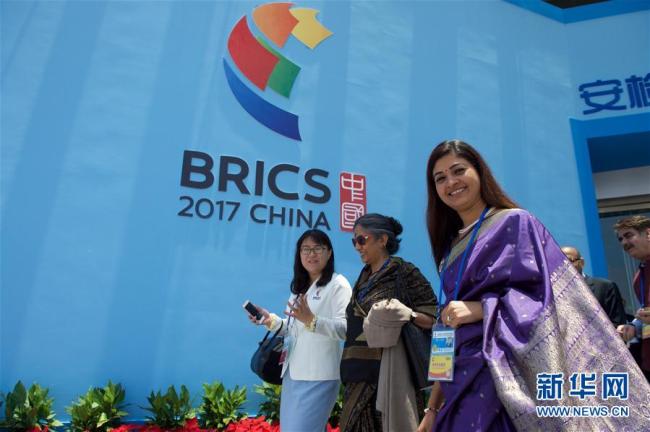 File photo of foreign delegates walking pass a BRICS sign. [Photo: Xinhua]