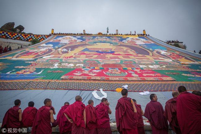 A huge Thangka painting bearing the image of the Buddha is displayed on the hillsides near the Drepung monastery in Lhasa, capital of Tibet Autonomous Region, on Saturday, Aug. 11, 2018. [Photo: VCG] 