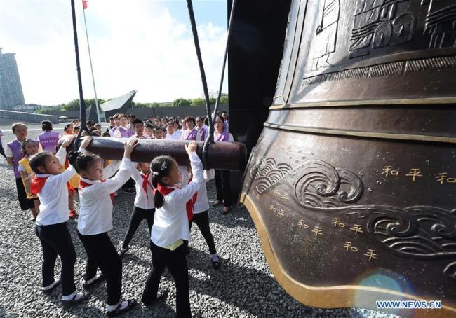 Students strike the Bell of Peace during a peace assembly at The Memorial Hall of the Victims in Nanjing Massacre by Japanese Invaders in east China's Jiangsu Province, Aug. 15, 2018. 
