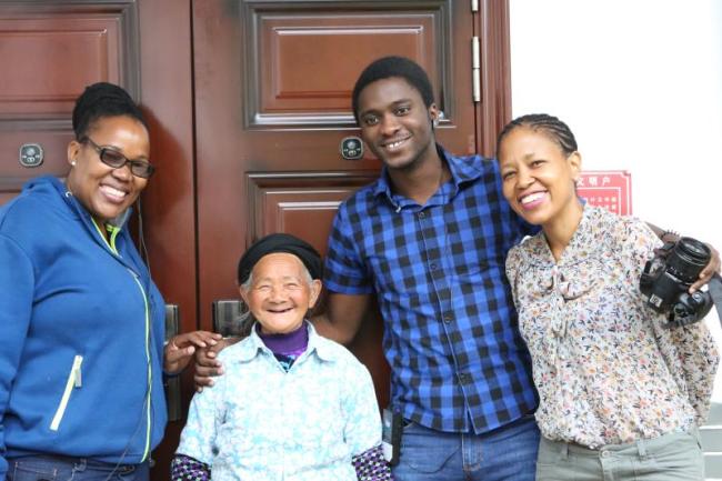 African representatives took a group photo with a Chinese grandma in front of her new resettlement house at Evergrande Xingfu Er'cun in Fengshan Township, Guizhou province on Thursday, August 16. [Photo: China Plus]