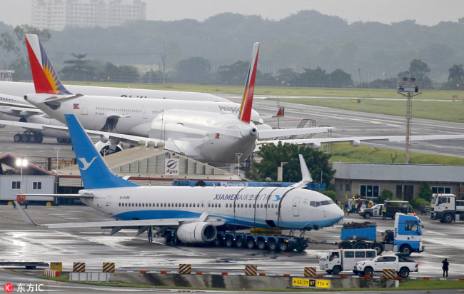 A Xiamen Air passenger plane from China is towed away from the site, more than 24-hours after it skidded off the runway while landing under a heavy downpour Saturday, Aug. 18, 2018, at the Ninoy Aquino International Airport in suburban Pasay city southeast of Manila, Philippines. [Photo: IC]