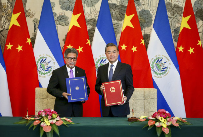 Chinese State Councilor and Foreign Minister Wang Yi (R) and EL Salvador Foreign Minister Carlos Castaneda sign a joint communique on the establishment of diplomatic relations in Diaoyutai State Guesthouse in Beijing on Tuesday. [Photo: China Daily/Xu JingXing]