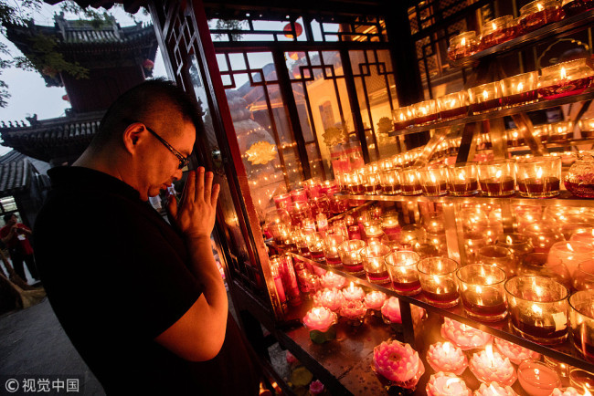 A man prays during a ceremony held at a Buddhist temple to honor the Ullambana Festival, known as China's Ghost Festival, in Beijing on Friday, August 17, 2018. [File Photo: VCG]