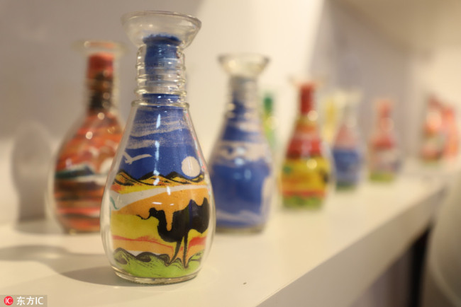 Paintings with colored sand in glass bottles made by An Nike on display at the shop. [Photo/IC] 