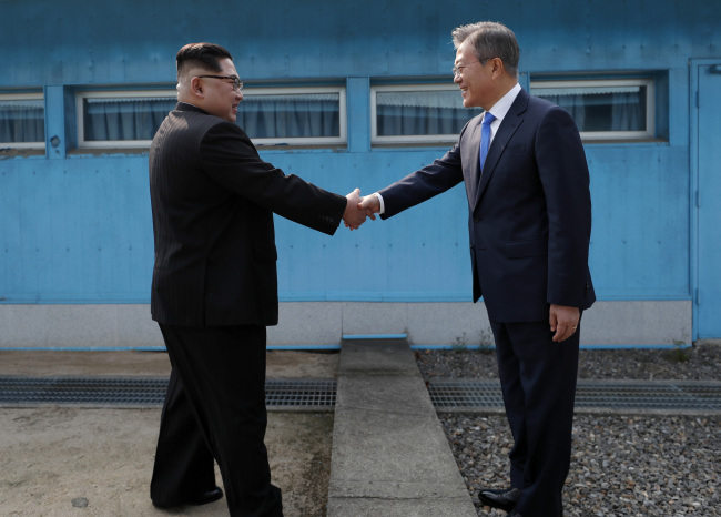 South Korean President Moon Jae-in and top leader of the Democratic People's Republic of Korea (DPRK) Kim Jong Un are holding hands at the southern military demarcation line of Panmunjom on the morning of April 27, 2018. [Photo: IC]